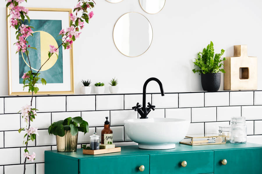 White bathroom with turquoise cabinets and black faucet.