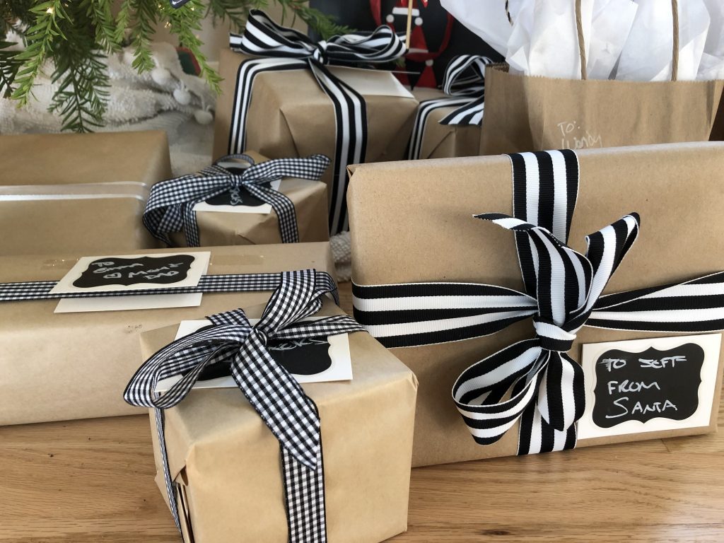 Gifts under the tree wrapped in brown butcher paper with black and white ribbon.