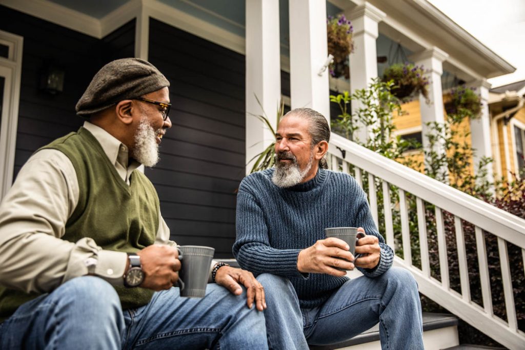 two men enjoying coffee and conversation on a front stoop
