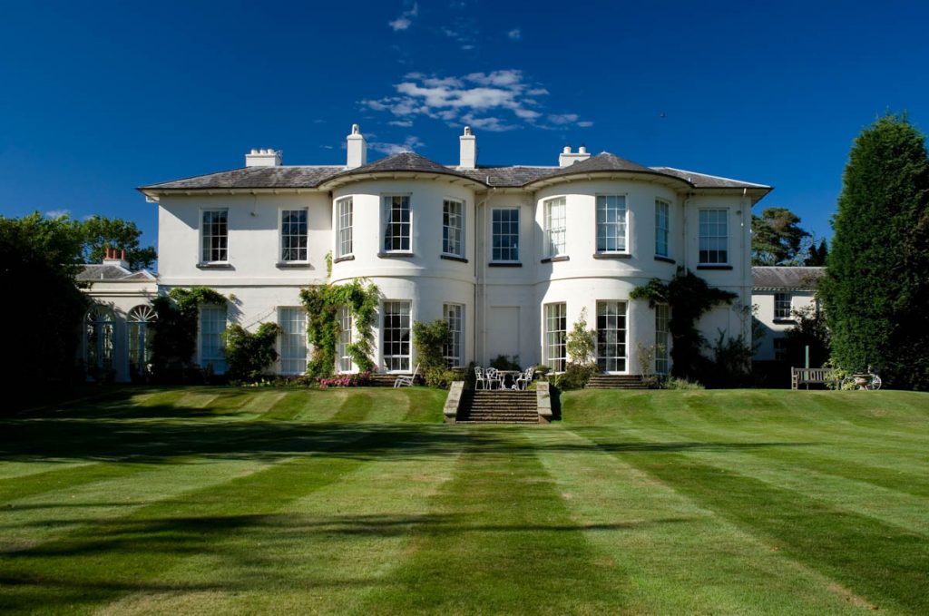 a white mansion with neatly mowed lawn under blue skies