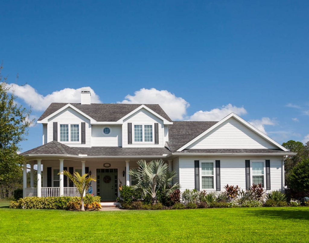 a traditional single family home, painted white, under blue skies