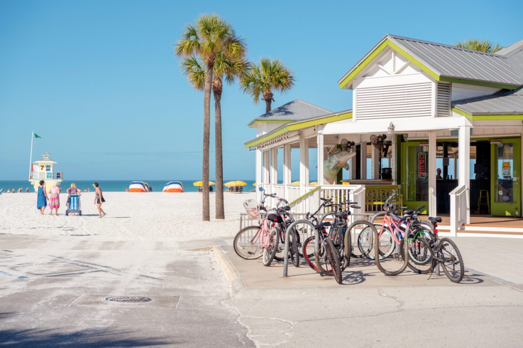 sunny beach with white sand and bicycles parked in the foreground