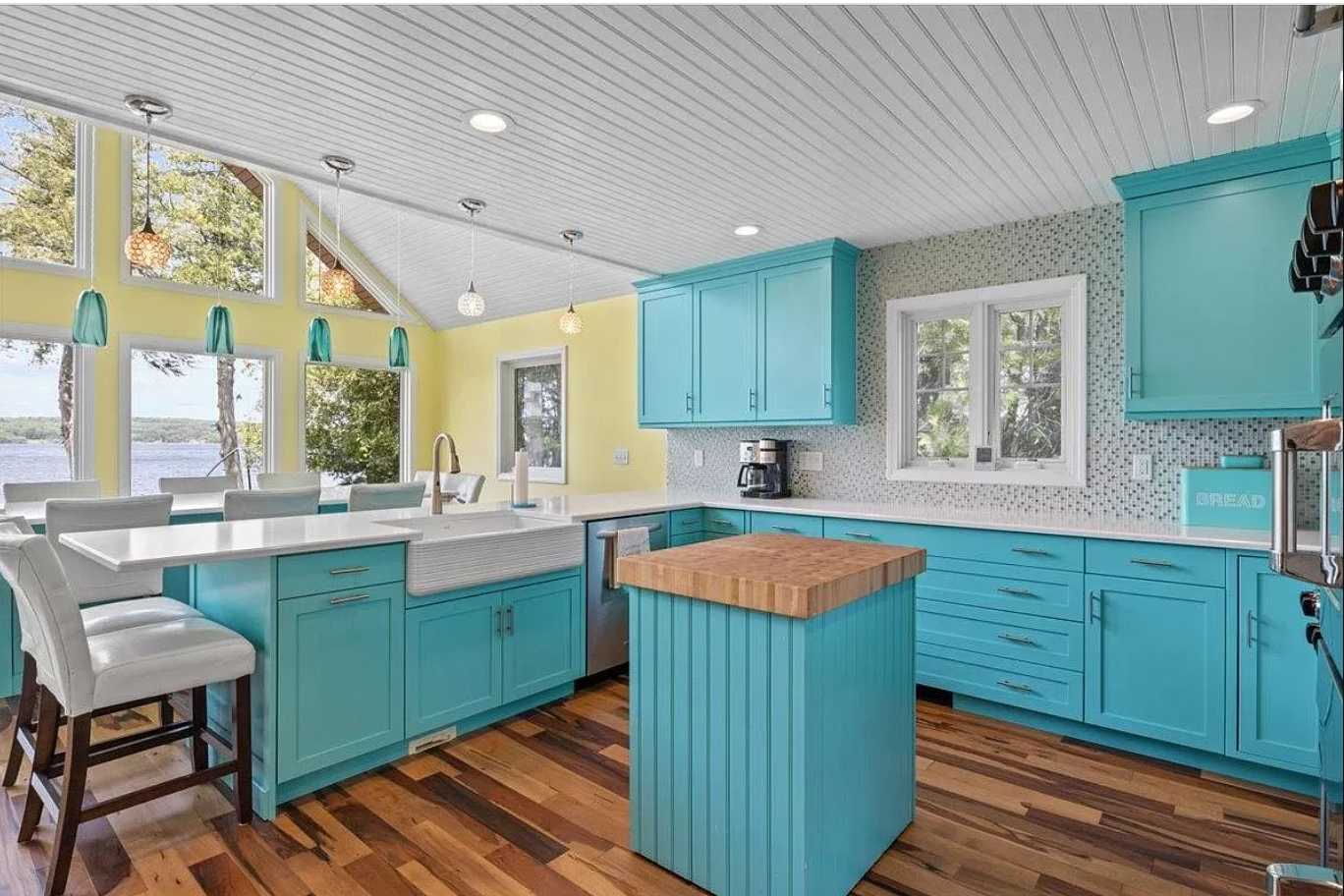 Image of a bright blue kitchen with hardwood floors.