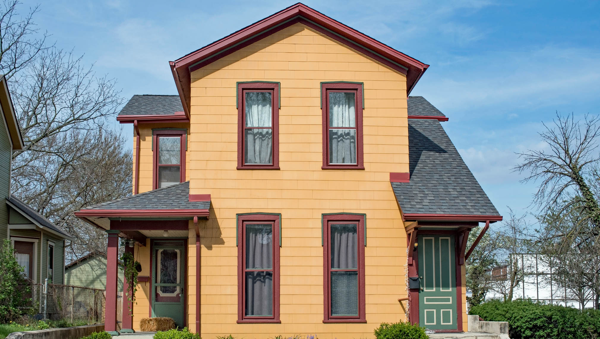 A dark yellow duplex with red trim and green doors