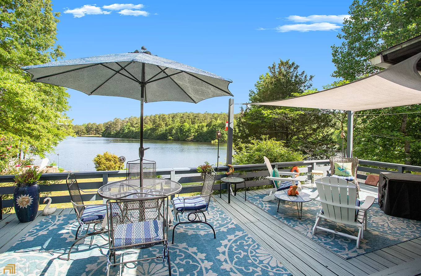 Image of a deck with a table and four chairs overlooking a lake.