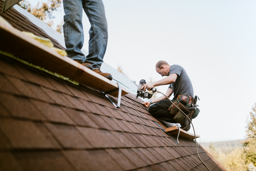 Two people doing repairs on a roof.