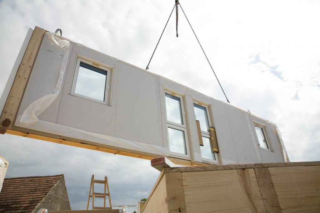 a crane hoists a prefabricated wall over another wall