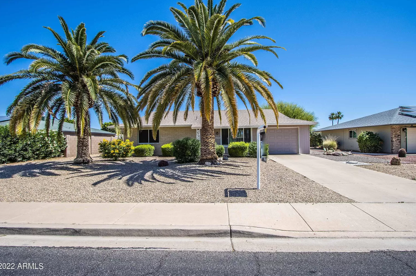 Charming houses: Image of a ranch home sitting behind two palm trees and against a blue sky.