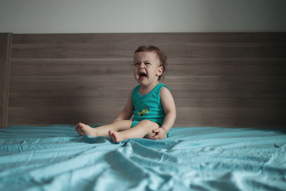 toddler crying on bed
