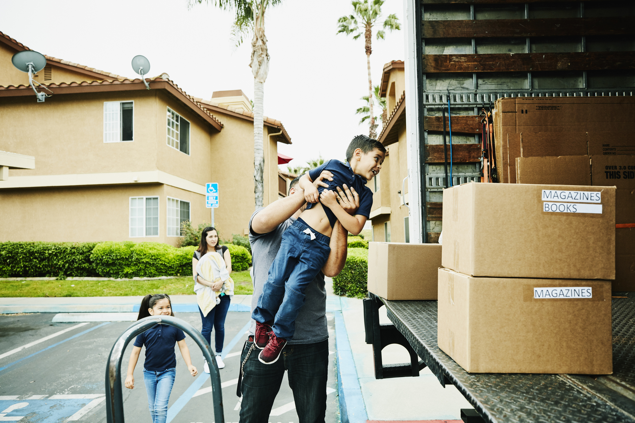 ather lifting smiling son into back of moving truck