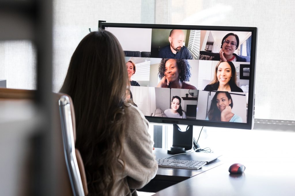 woman looking at computer screen which has a series of video conference screens on it