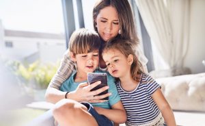 Young mother and two children look at homes on a smart phone