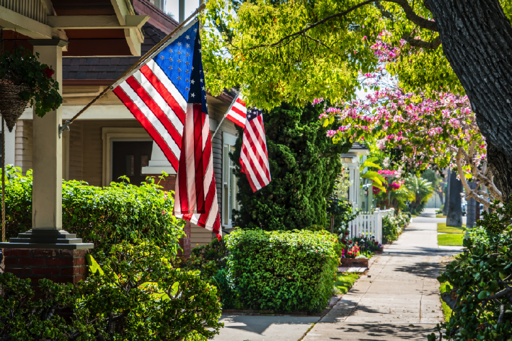 Leafy suburban neighborhood with American flags hung from houses