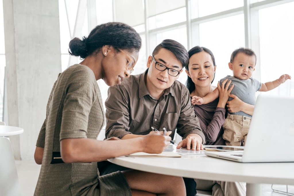 Young couple with baby signing document with lender