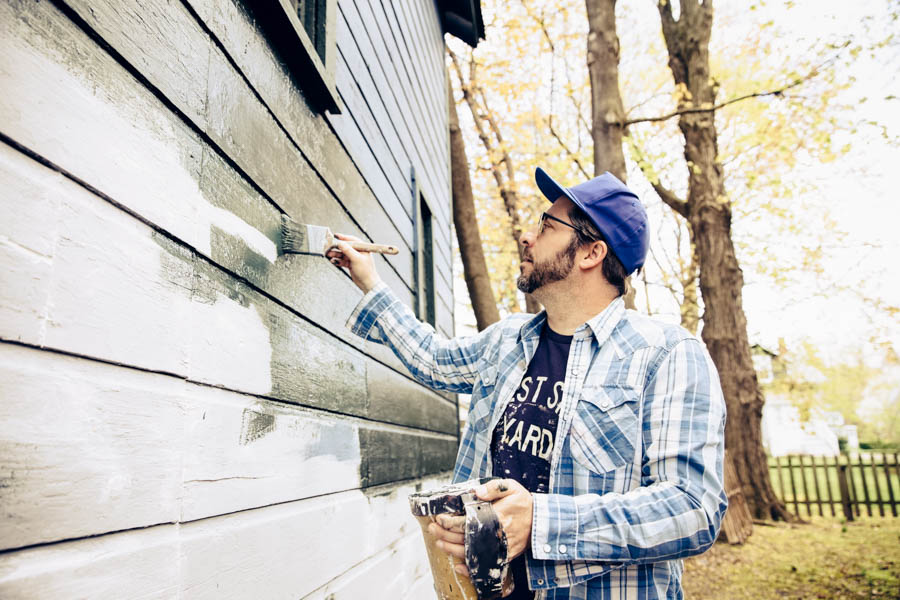 Side view of man painting exterior of home