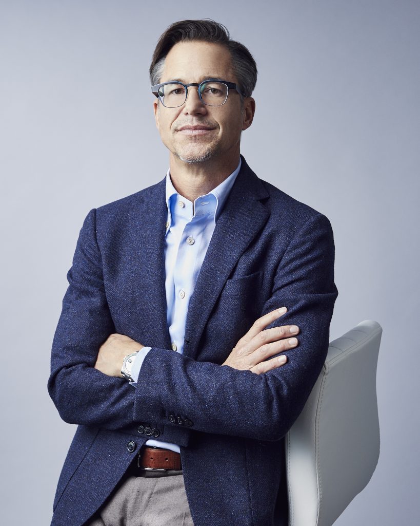 Zillow CEO Rich Barton wearing navy blue sportcoat, his arms crossed over his waist